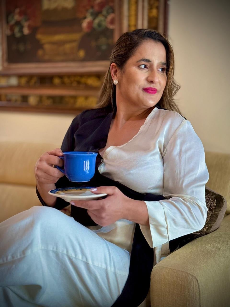 Adriana Costa em um momento de pausa, segurando uma xícara de café